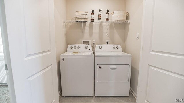 laundry area with washing machine and clothes dryer and light tile patterned floors