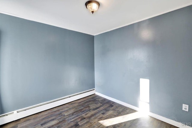 spare room featuring dark hardwood / wood-style flooring and a baseboard heating unit