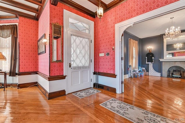 foyer entrance featuring hardwood / wood-style flooring, lofted ceiling with beams, ornamental molding, and an inviting chandelier