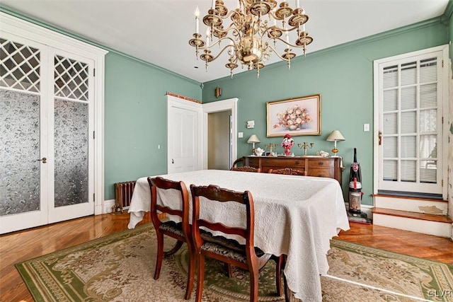 dining area with ornamental molding, a notable chandelier, and wood-type flooring