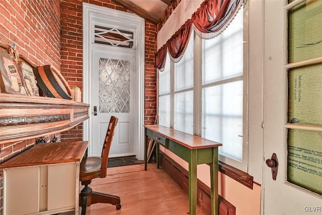 office featuring light hardwood / wood-style flooring, brick wall, and lofted ceiling