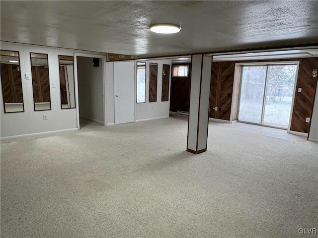 carpeted spare room with a textured ceiling, a healthy amount of sunlight, and wood walls