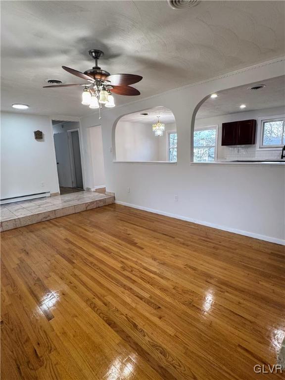 spare room featuring hardwood / wood-style floors, ceiling fan with notable chandelier, baseboard heating, and a textured ceiling