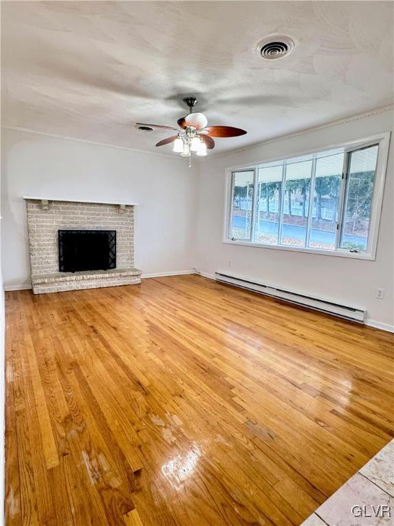 unfurnished living room with baseboard heating, ceiling fan, light hardwood / wood-style flooring, and a brick fireplace