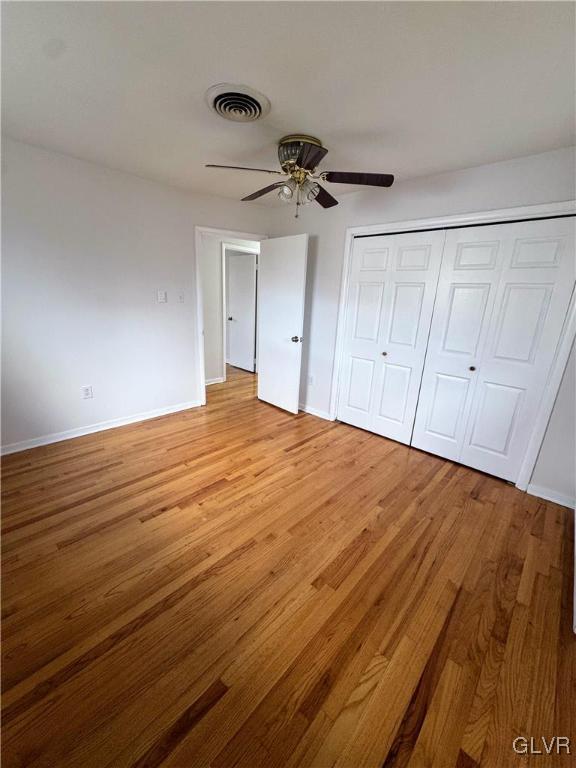 unfurnished bedroom with light wood-type flooring, a closet, and ceiling fan