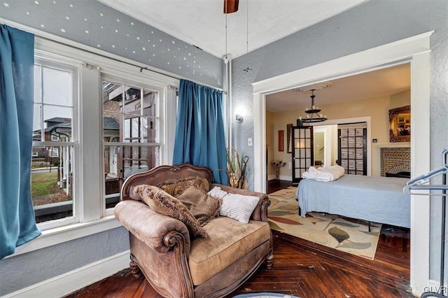 bedroom with ceiling fan, parquet flooring, and a brick fireplace