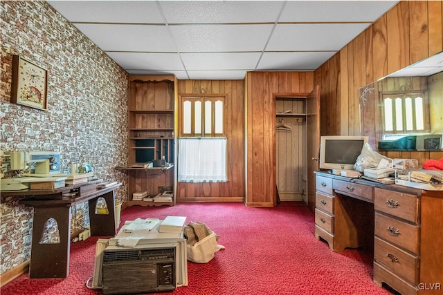 home office with carpet floors, a drop ceiling, and wood walls