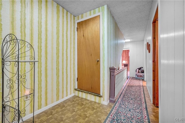 hallway with wood walls, light parquet floors, and a textured ceiling