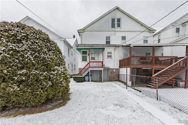 snow covered rear of property featuring a deck