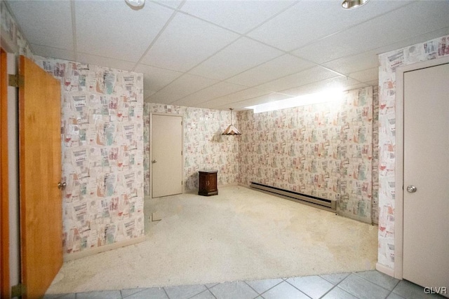 basement featuring a paneled ceiling and baseboard heating