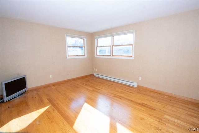 empty room with hardwood / wood-style flooring and a baseboard heating unit