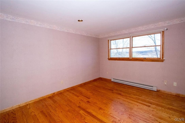 unfurnished room with hardwood / wood-style floors and a baseboard radiator