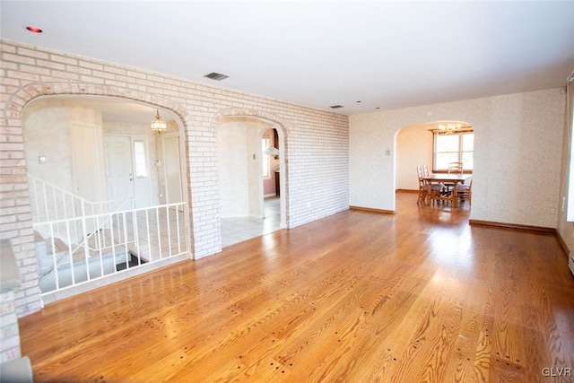 empty room with wood-type flooring and brick wall