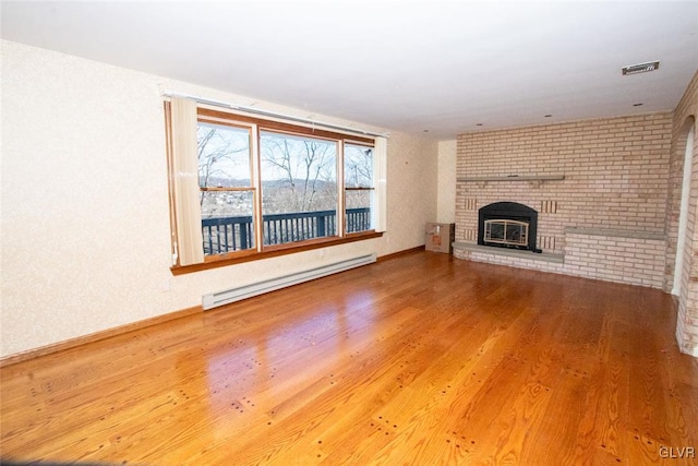 unfurnished living room with hardwood / wood-style flooring and a baseboard heating unit