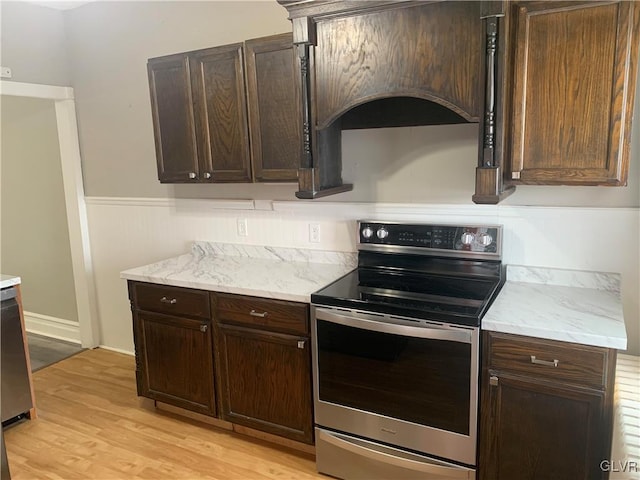 kitchen with dark brown cabinetry, stainless steel electric range oven, and light wood-type flooring