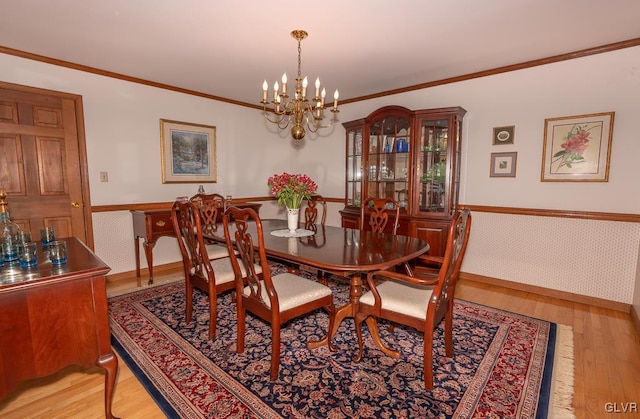 dining area with a notable chandelier, light hardwood / wood-style floors, and ornamental molding