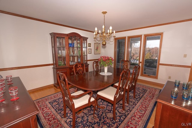 dining room featuring hardwood / wood-style floors, ornamental molding, and an inviting chandelier