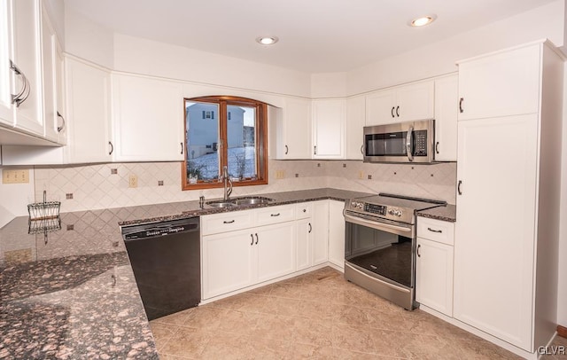 kitchen with white cabinetry, sink, dark stone countertops, decorative backsplash, and appliances with stainless steel finishes