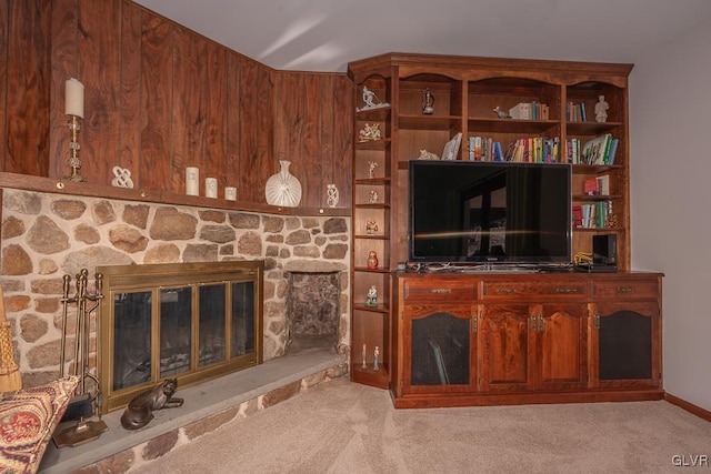 carpeted living room featuring a fireplace and wooden walls