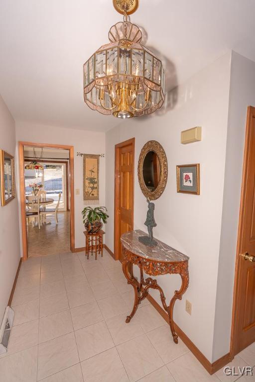 hallway featuring light tile patterned floors and a notable chandelier