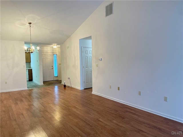 spare room with hardwood / wood-style floors, lofted ceiling, and a notable chandelier