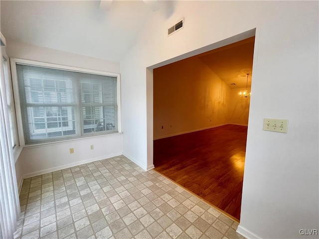 spare room featuring vaulted ceiling and an inviting chandelier