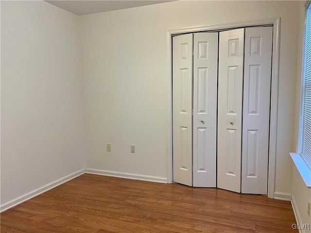 unfurnished bedroom with wood-type flooring and a closet