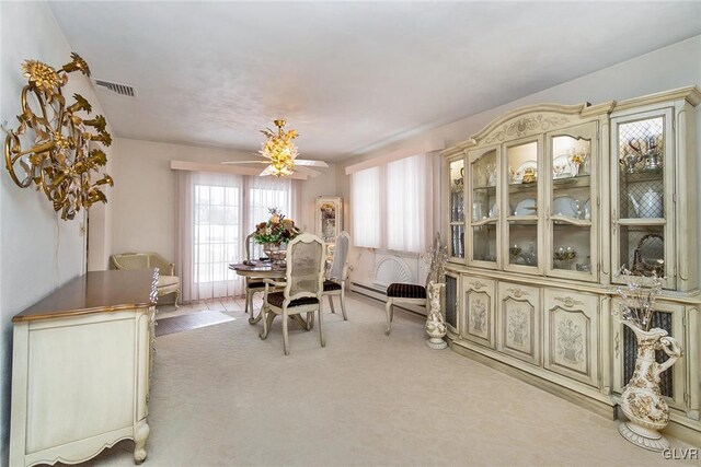 dining space with ceiling fan and light carpet