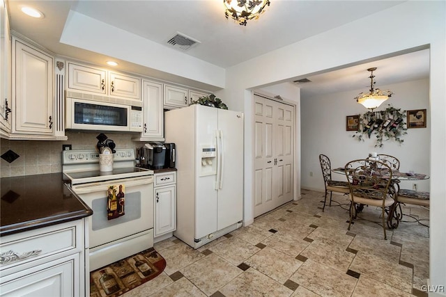 kitchen with decorative backsplash, white cabinets, pendant lighting, and white appliances