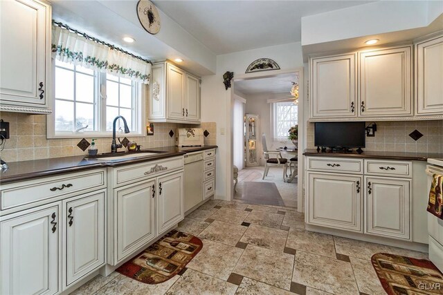 kitchen featuring white dishwasher, tasteful backsplash, and sink