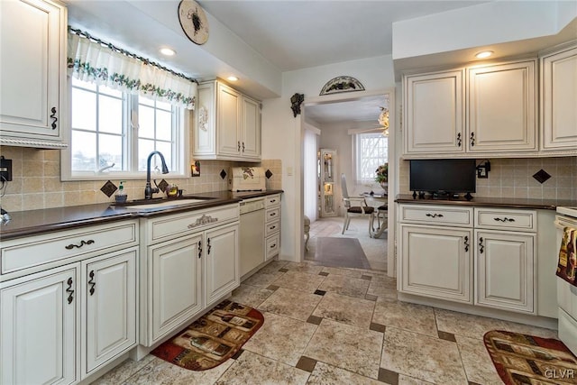 kitchen featuring white dishwasher, sink, and decorative backsplash