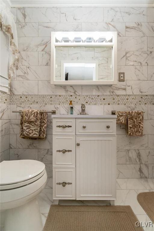 bathroom featuring vanity, tile walls, and toilet