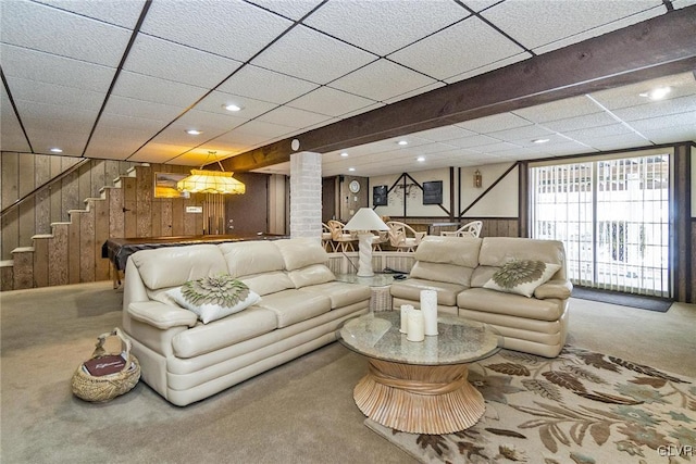 carpeted living room with a drop ceiling and wooden walls