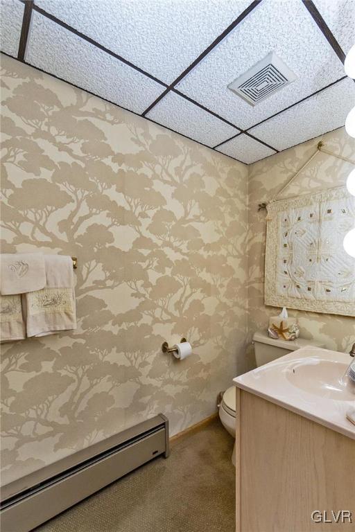 bathroom featuring a paneled ceiling, vanity, toilet, and baseboard heating