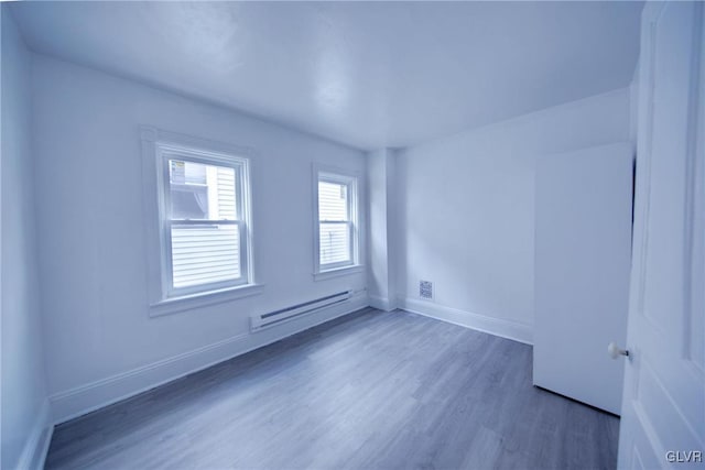 unfurnished room featuring dark wood-type flooring and a baseboard heating unit