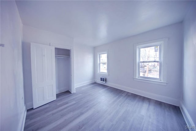 unfurnished bedroom with multiple windows, wood-type flooring, and a closet