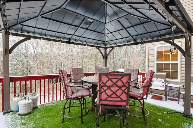 wooden terrace featuring outdoor dining area, a lawn, and a gazebo