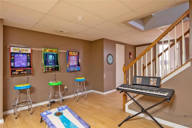 exercise area with a paneled ceiling, visible vents, baseboards, and wood finished floors