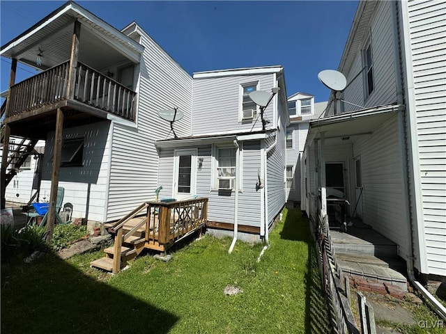 rear view of house featuring a lawn, a wooden deck, and a balcony