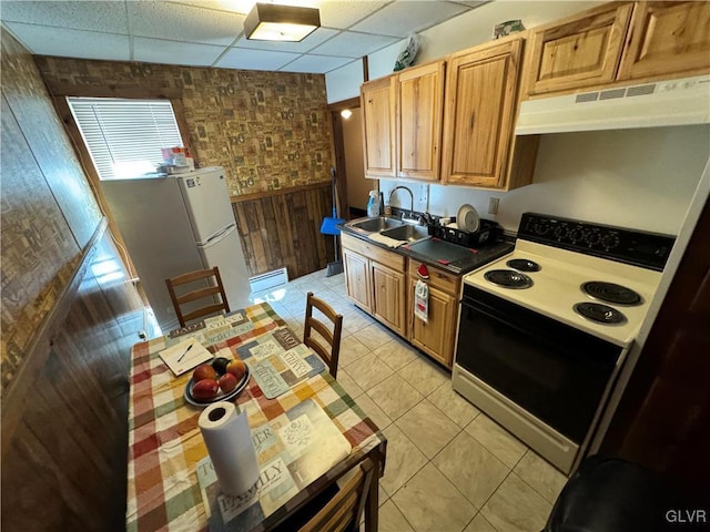 kitchen with sink, wood walls, white appliances, a paneled ceiling, and light tile patterned flooring