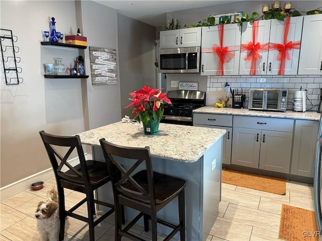 kitchen featuring a kitchen island, light stone counters, a breakfast bar area, and appliances with stainless steel finishes