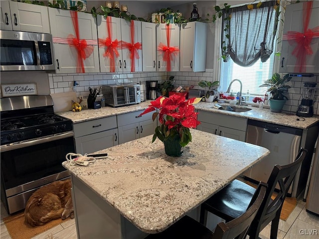 kitchen featuring appliances with stainless steel finishes, backsplash, a kitchen island, and sink