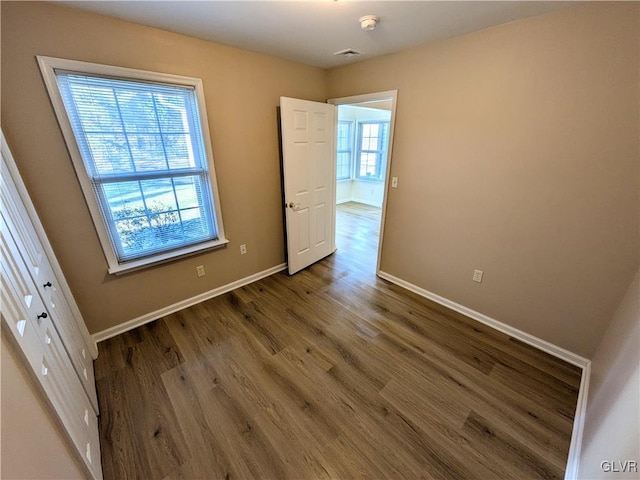 unfurnished bedroom featuring wood-type flooring, a closet, and multiple windows