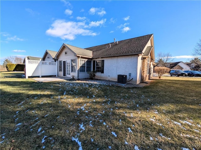 rear view of house featuring cooling unit and a lawn