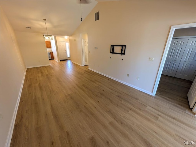 unfurnished living room featuring hardwood / wood-style floors, vaulted ceiling, and a chandelier