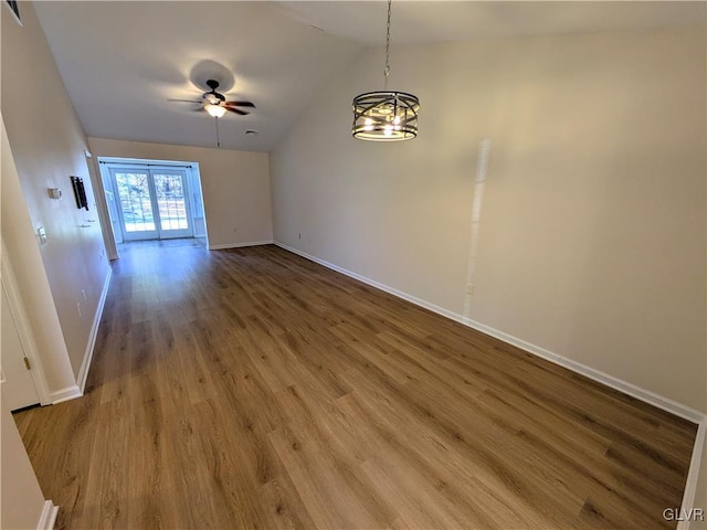 spare room featuring ceiling fan with notable chandelier, wood-type flooring, and lofted ceiling