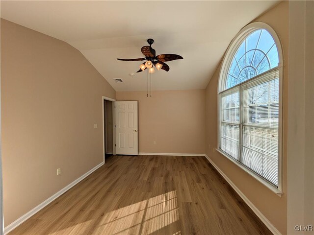 empty room with lofted ceiling, ceiling fan, and hardwood / wood-style floors