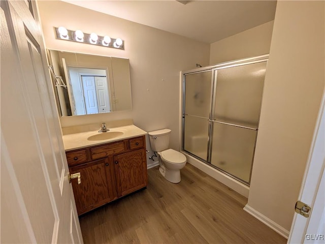 bathroom featuring vanity, toilet, a shower with shower door, and wood-type flooring