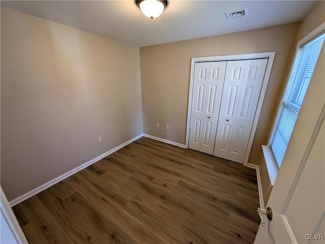 unfurnished bedroom featuring a closet and dark hardwood / wood-style flooring