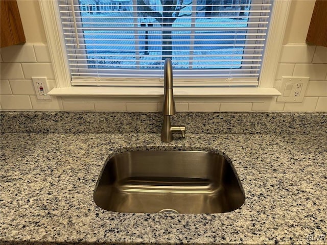 interior details featuring stone countertops, tasteful backsplash, and sink